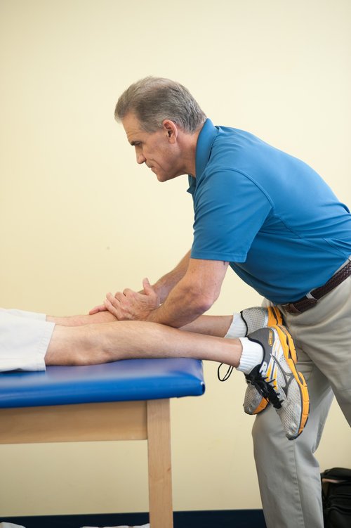 therapist massaging patients right calf